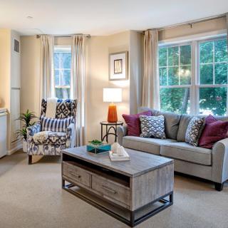 A cozy living room with stylish decor, featuring a comfortable sofa, patterned armchair, and a modern coffee table.