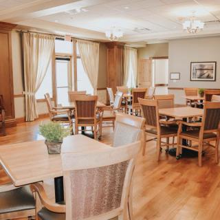 A cozy dining room with wooden tables and chairs, featuring elegant curtains and a warm atmosphere.