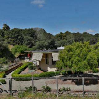 A picturesque house surrounded by lush greenery under a clear blue sky.
