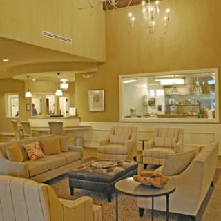 A cozy living room with sofas and a coffee table, illuminated by a chandelier.