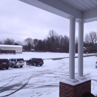 A winter scene featuring snow-covered ground and parked vehicles under a cloudy sky.