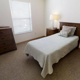 A minimalist bedroom with a single bed, wooden furniture, and soft lighting.