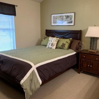 A cozy bedroom with a neatly made bed, nightstand, and lamp.