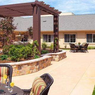 A sunny patio area with comfortable outdoor seating, a garden, and a pergola for shade.