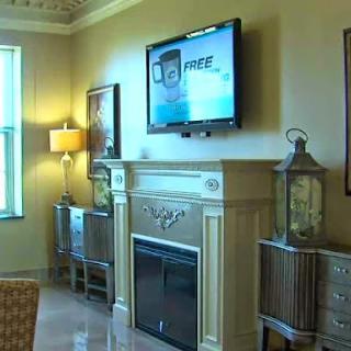 A cozy living room featuring a modern television above a decorative fireplace, complemented by stylish furniture and warm lighting.