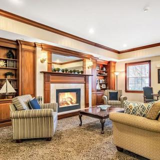 A cozy living room with a fireplace, surrounded by comfortable furniture and wooden shelves.