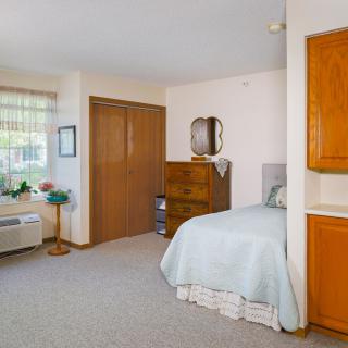 A cozy bedroom with a single bed, dresser, and window.