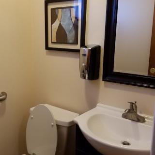A small bathroom with a sink, toilet, and framed wall art.