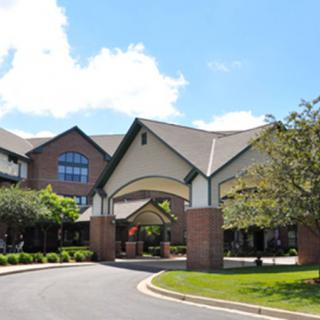 An elegant building with a welcoming entrance, surrounded by well-maintained landscaping under a clear blue sky.