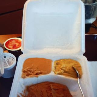 A takeout meal featuring two different types of sauce in a styrofoam container.