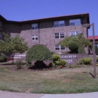 A college building surrounded by greenery and trees on a sunny day.