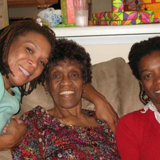 A joyful family moment with three people smiling together on a couch.