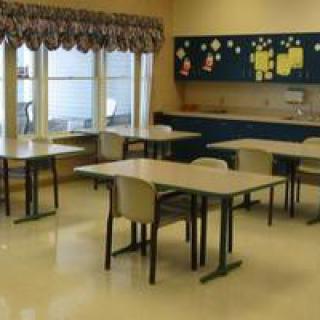 An empty classroom with several tables and chairs arranged.