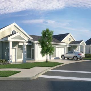 A suburban neighborhood with modern houses and parked cars under a clear blue sky.