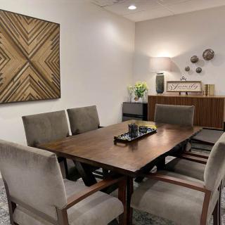 A modern dining room featuring a wooden table, upholstered chairs, and wall art.