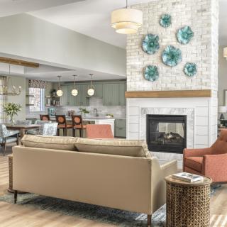 A modern living room with an open kitchen, featuring stylish furniture and a decorative fireplace.