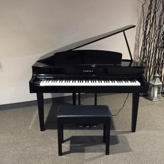 A sleek black grand piano with a matching bench in a modern room.