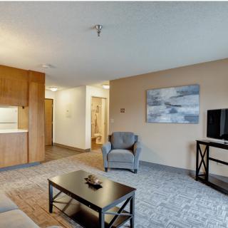 A modern living room with neutral colors, featuring a comfortable armchair, a coffee table, and a television.