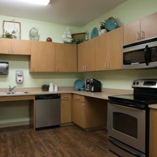 A modern kitchen featuring wooden cabinets, essential appliances, and a soothing green color scheme.