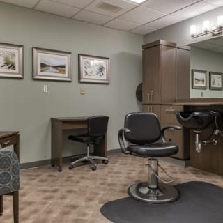 A well-organized salon interior with a barber chair, mirrors, and framed artwork on the walls.