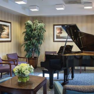 A cozy living room featuring a grand piano, seating area, and decorative plants.