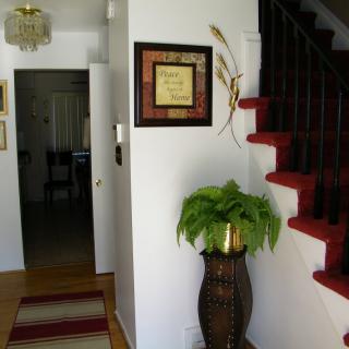 A cozy home interior featuring a staircase, decorative plant in a vase, and framed wall art.