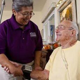 A caregiver assisting an elderly man at home, providing healthcare support.