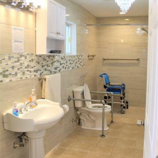 An accessible bathroom with a sink, toilet, and grab bars designed for wheelchair access.