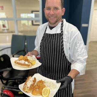 A chef proudly presents two beautifully plated meals.