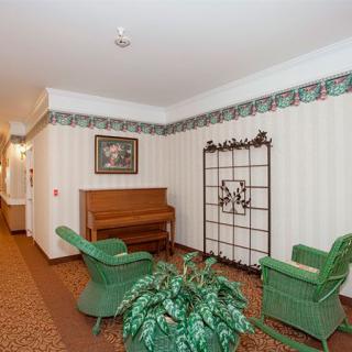 A cozy hallway with a piano, wicker chairs, and decorative elements.