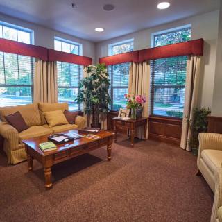 A cozy living room with comfortable sofas, a wooden coffee table, and large windows adorned with curtains.