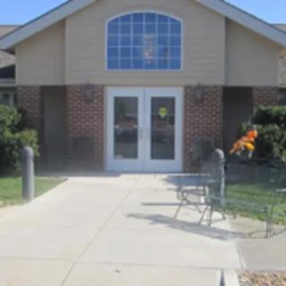 A building entrance with glass doors and a concrete sidewalk leading up to it.
