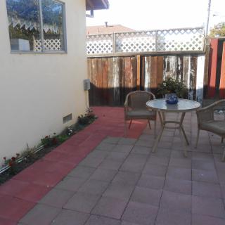 A cozy patio area with a table and chairs, surrounded by a fenced enclosure.