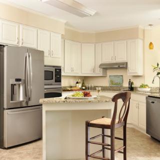 A modern kitchen featuring light-colored cabinetry, stainless steel appliances, and a cozy island setup.