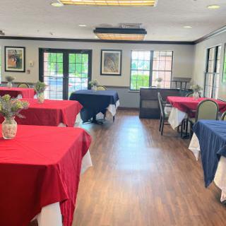 A cozy dining room setup featuring tables adorned with red and blue tablecloths, creating an inviting atmosphere.
