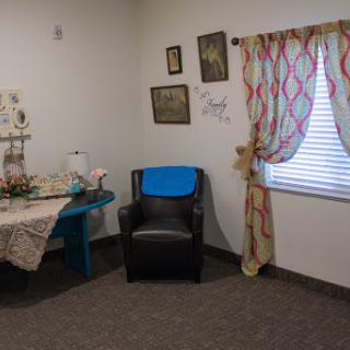 A cozy corner of a living room featuring a comfortable chair, a colorful table, and decorative elements.