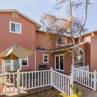 A two-story residential house with a fenced backyard deck and trees.