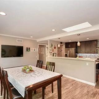 A modern dining area with wood flooring and an open layout leading to the kitchen, featuring a skylight for natural light.