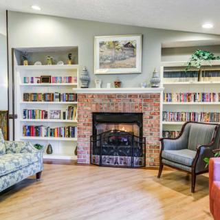 A cozy living room featuring a fireplace surrounded by bookshelves, with comfortable chairs inviting relaxation.