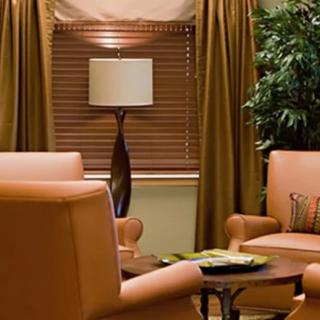 A cozy living room with leather chairs, a floor lamp, and lush curtains.