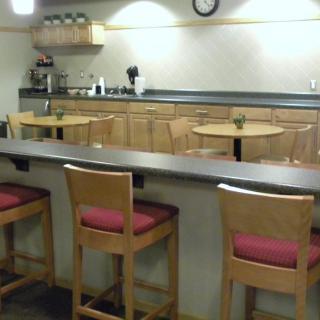 A cozy kitchen and cafe seating area with a counter and wooden chairs.