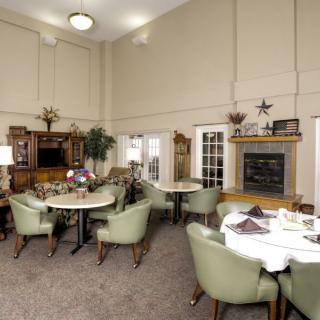 A cozy dining area with multiple tables and chairs, a fireplace, and elegant decor.