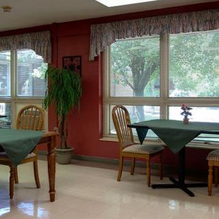 A cozy dining area with tables and chairs near large windows letting in natural light.