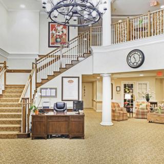 A spacious and welcoming lobby with a central staircase, reception desk, and comfortable seating.