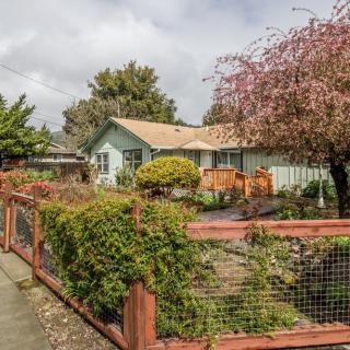 A quaint house with a lush garden and wooden fence on a cloudy day.