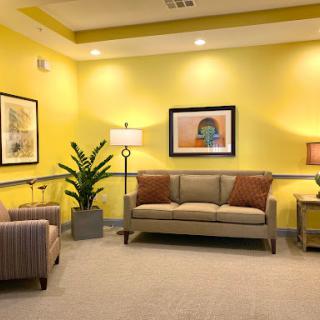 A cozy waiting room featuring yellow walls, comfortable seating, and decorative elements.