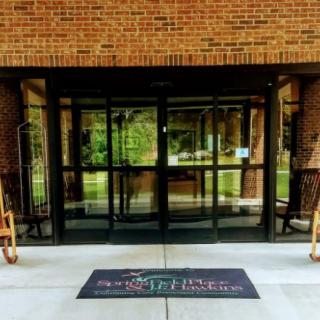 The entrance of a building with glass doors and a welcome mat.