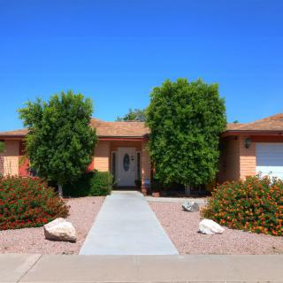 A single-story house with desert landscaping and a clear blue sky.