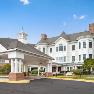 A modern senior living facility with a welcoming entrance and landscaped surroundings.