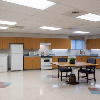 A modern kitchen space featuring wooden cabinetry, a dining table with chairs, and essential appliances.